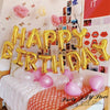 A set of thirteen rose gold foil letter balloons spelling out HAPPY BIRTHDAY for a party decoration.