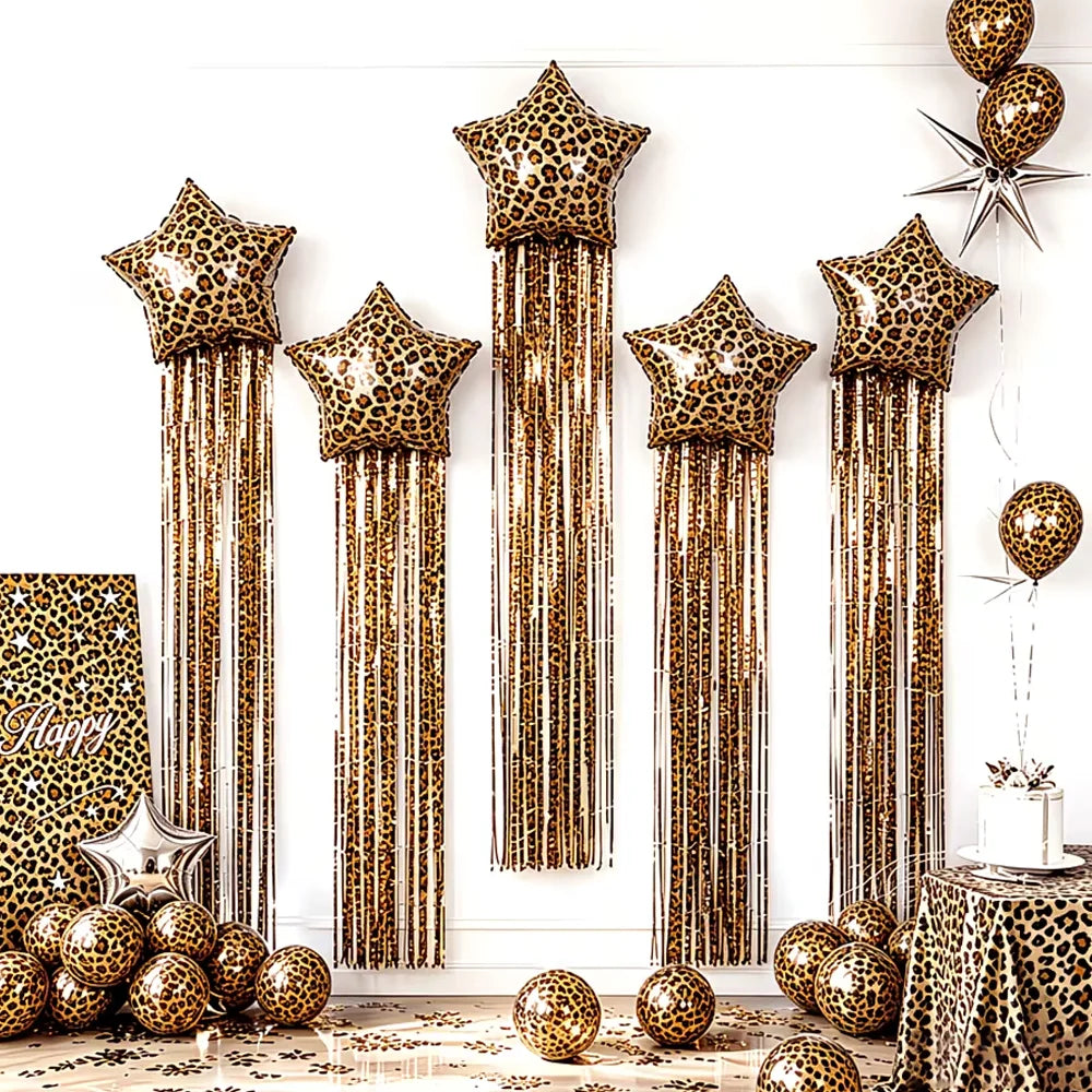 A display of leopard print star balloons with long gold tassels against a white wall.