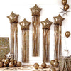 A display of leopard print star balloons with long gold tassels against a white wall.