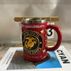 Taza de café roja con temática militar, letras doradas y asa de color bronce.