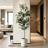 A lifelike artificial olive tree in a white pot displayed indoors against a modern wall.