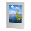A white magnetic double-sided frame displaying a scenic view of water, sky, and a green tree.