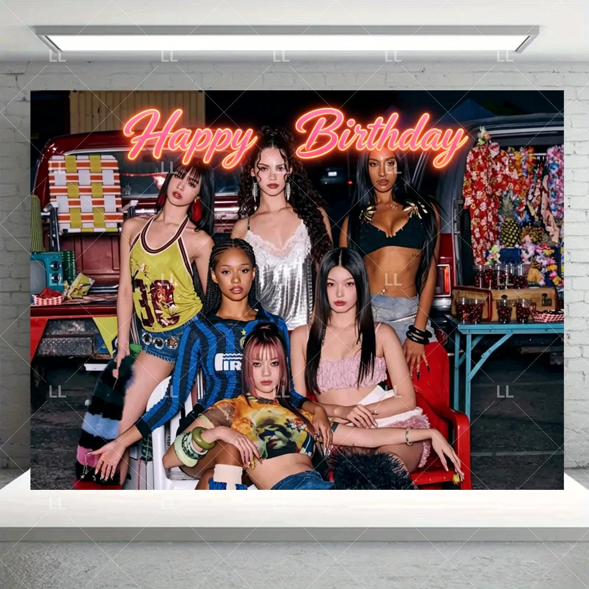 A group of five women posing in front of a festive birthday backdrop with neon text and colorful decorations.