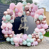 A balloon garland arch made of pastel pink and green balloons for a baby shower or party decoration.