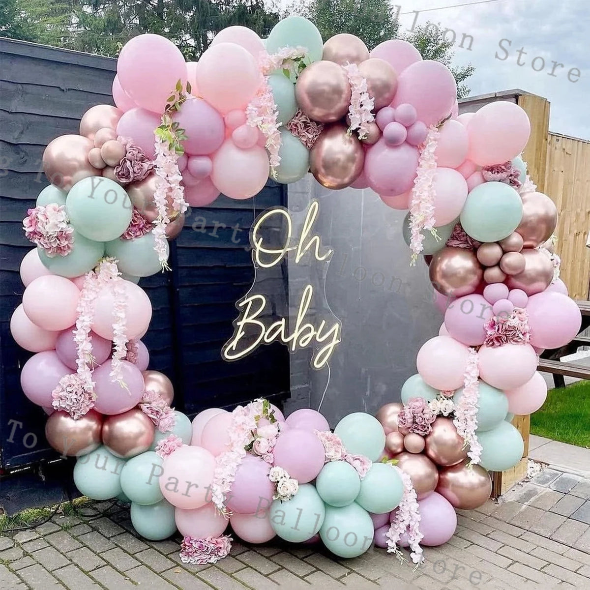 A balloon garland arch made of pastel pink and green balloons for a baby shower or party decoration.