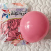 A single, large, glossy pink latex balloon is shown on a white surface next to packaging.