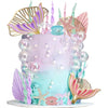 A tiered mermaid cake decorated with purple and pink floral toppers, iridescent pearls, and sea elements.