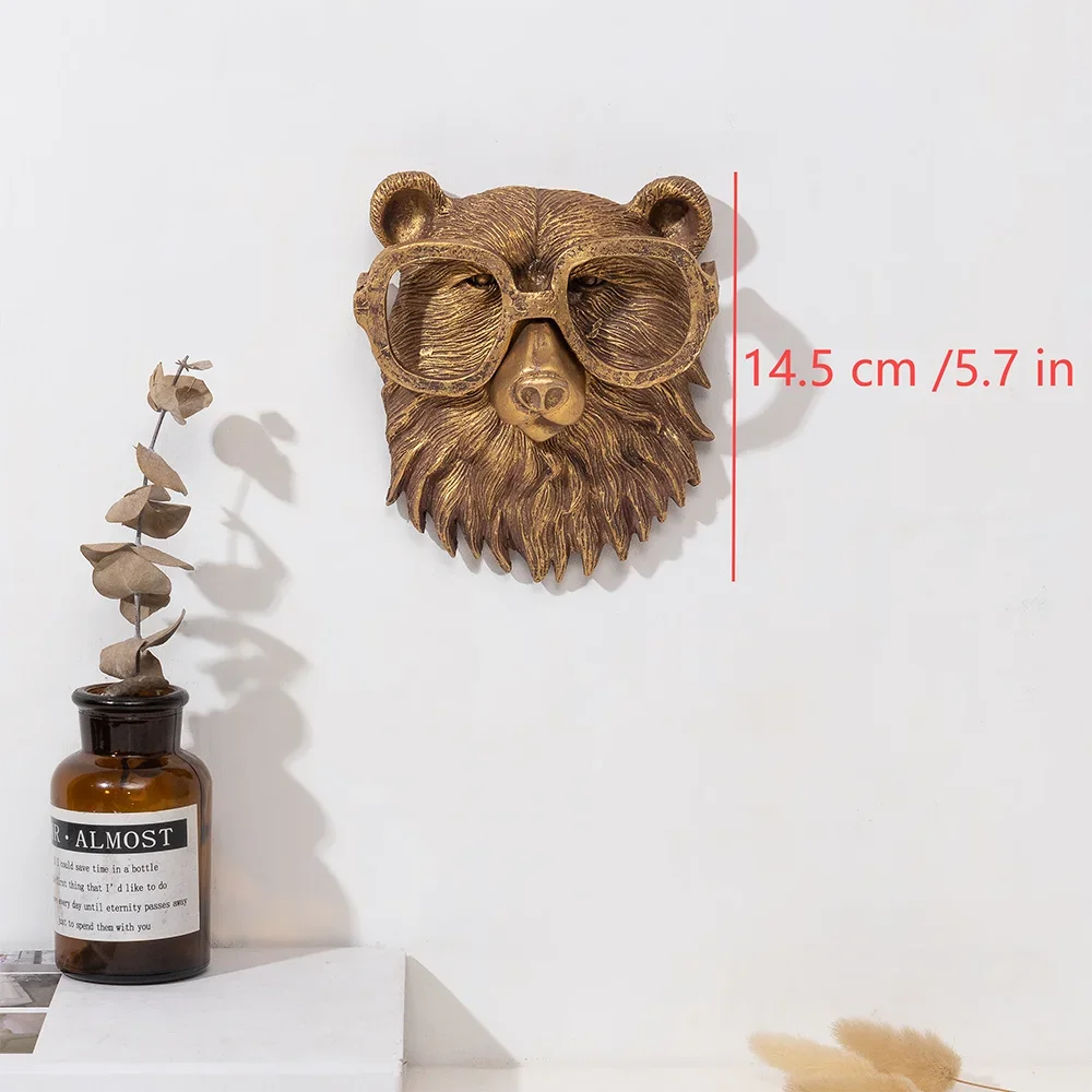 A bronze deer head storage hook wall decor mounted on a white wall next to a glass bottle.