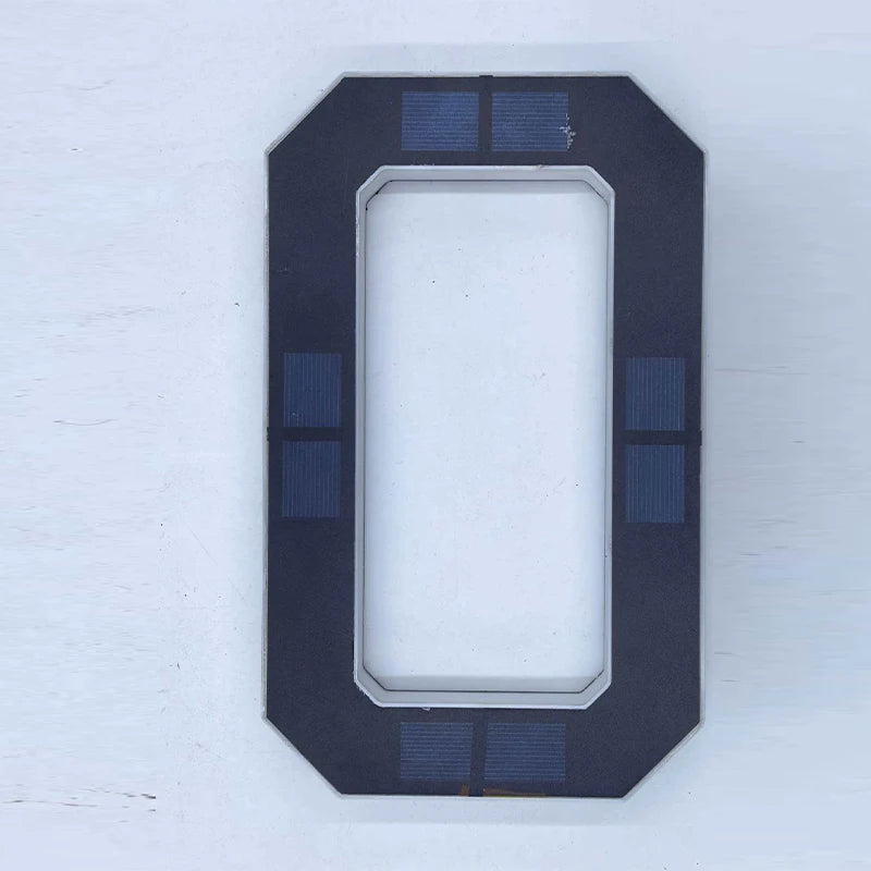 Un letrero rectangular oscuro con un corte vertical y pequeños paneles solares en los bordes superior e inferior.