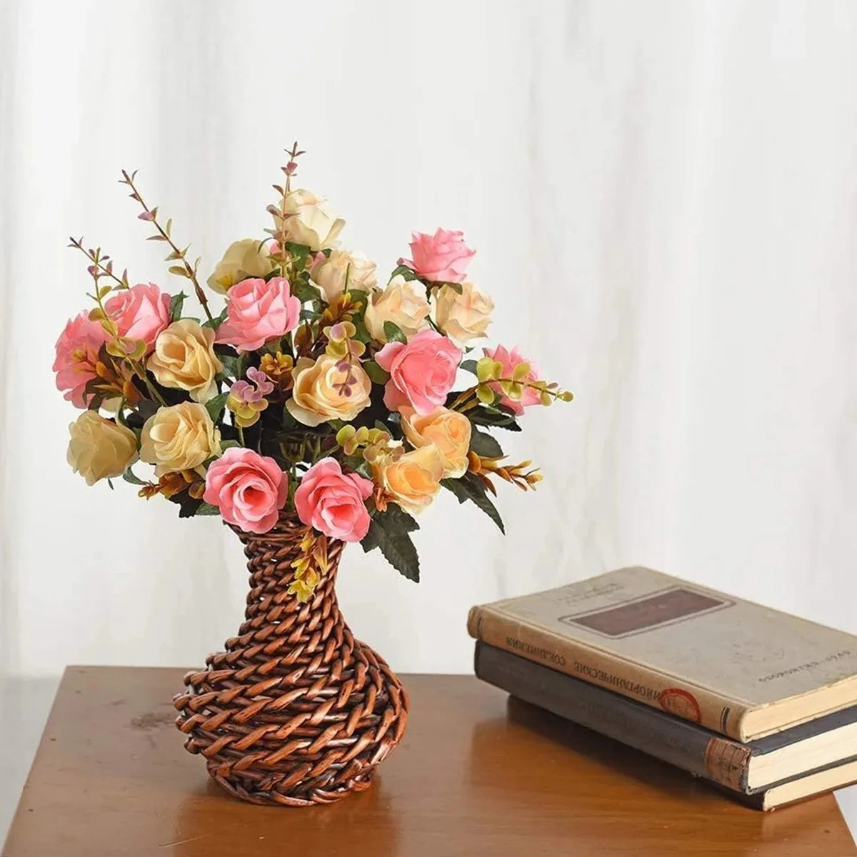A bouquet of realistic silk rose flowers in shades of pink and cream arranged in a woven vase.