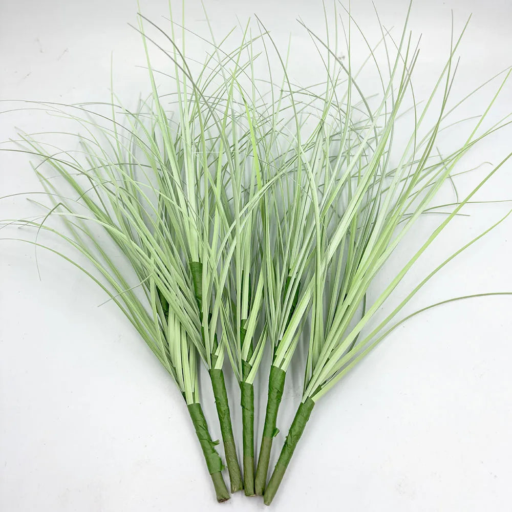 A bundle of artificial grass greenery with slender, light green blades and thick stems.