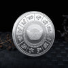 A silver collectible coin featuring various mythical creatures and a central dragon design on a dark background.