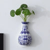 Antique blue and white ceramic wall vase with green foliage