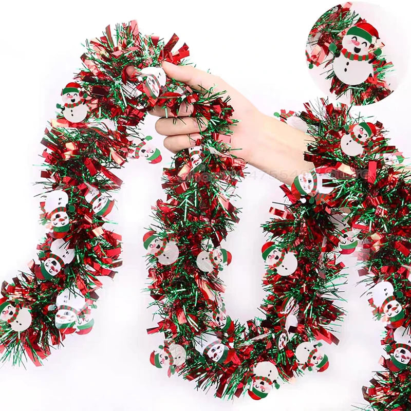A hand is holding a festive Christmas tinsel garland decorated with reindeer and snowmen faces.