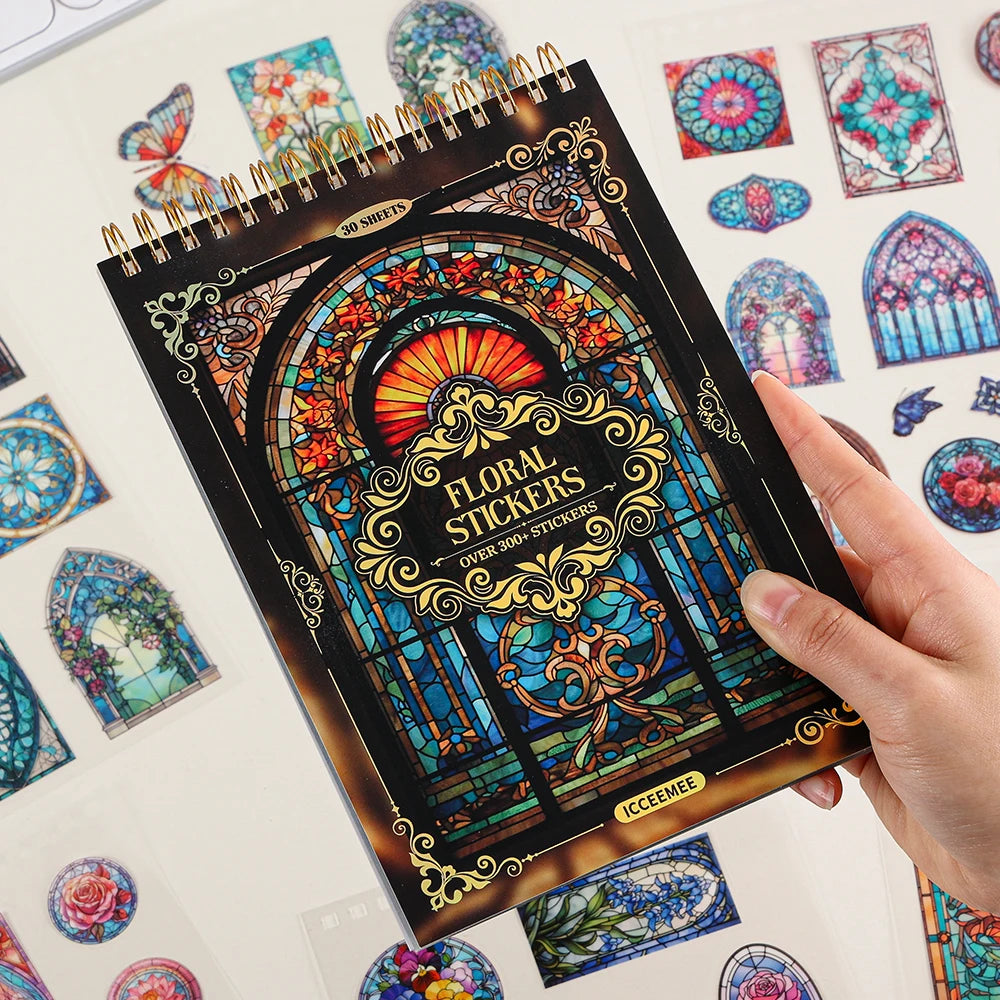A hand holds a sheet of vintage floral window scrapbooking stickers featuring colorful stained glass designs.