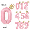 A set of pink aluminum foil crown number balloons spelling out 012456789 with a large zero and a thirty-two inch balloon.