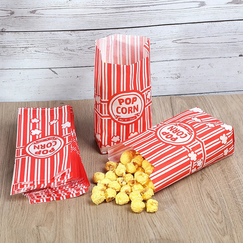 Red and white striped popcorn buckets with popcorn displayed on a wooden surface.