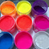 A collection of 13 vivid neon fluorescent pigment powders in various bright colors including orange, yellow, pink, purple, an
