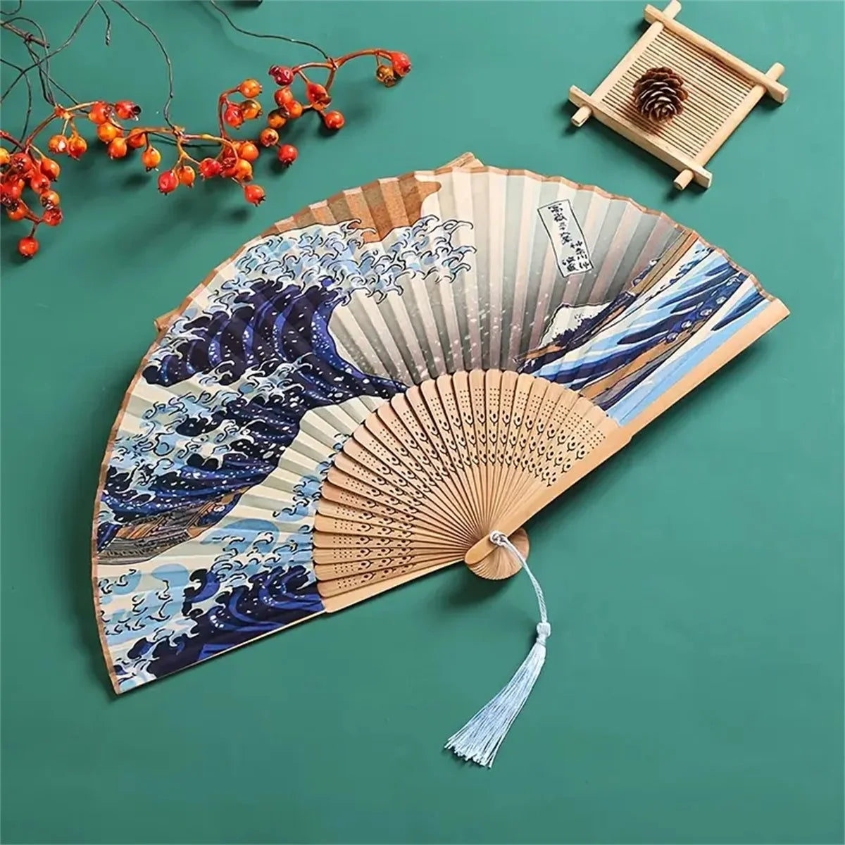 A Japanese foldable hand fan featuring a detailed Kanagawa wave design on light and blue tones.