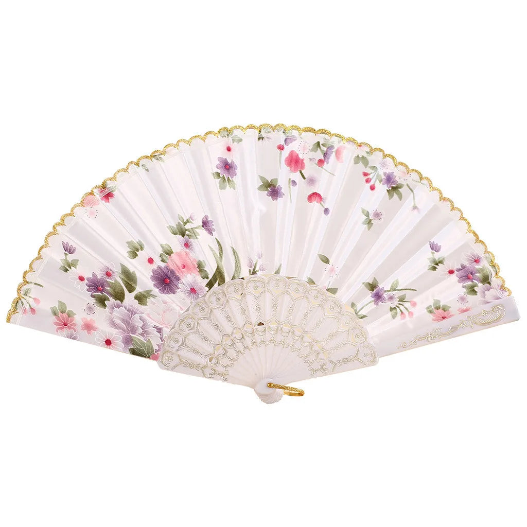 A vintage lace hand fan with a pleated white surface decorated with pink and purple floral patterns.