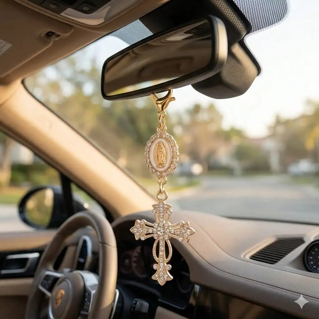 A gold pearl rhinestone cross keychain charm hanging from a rearview mirror inside a car.