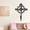 Black metal cross wall art with thorn details mounted on a white wall.