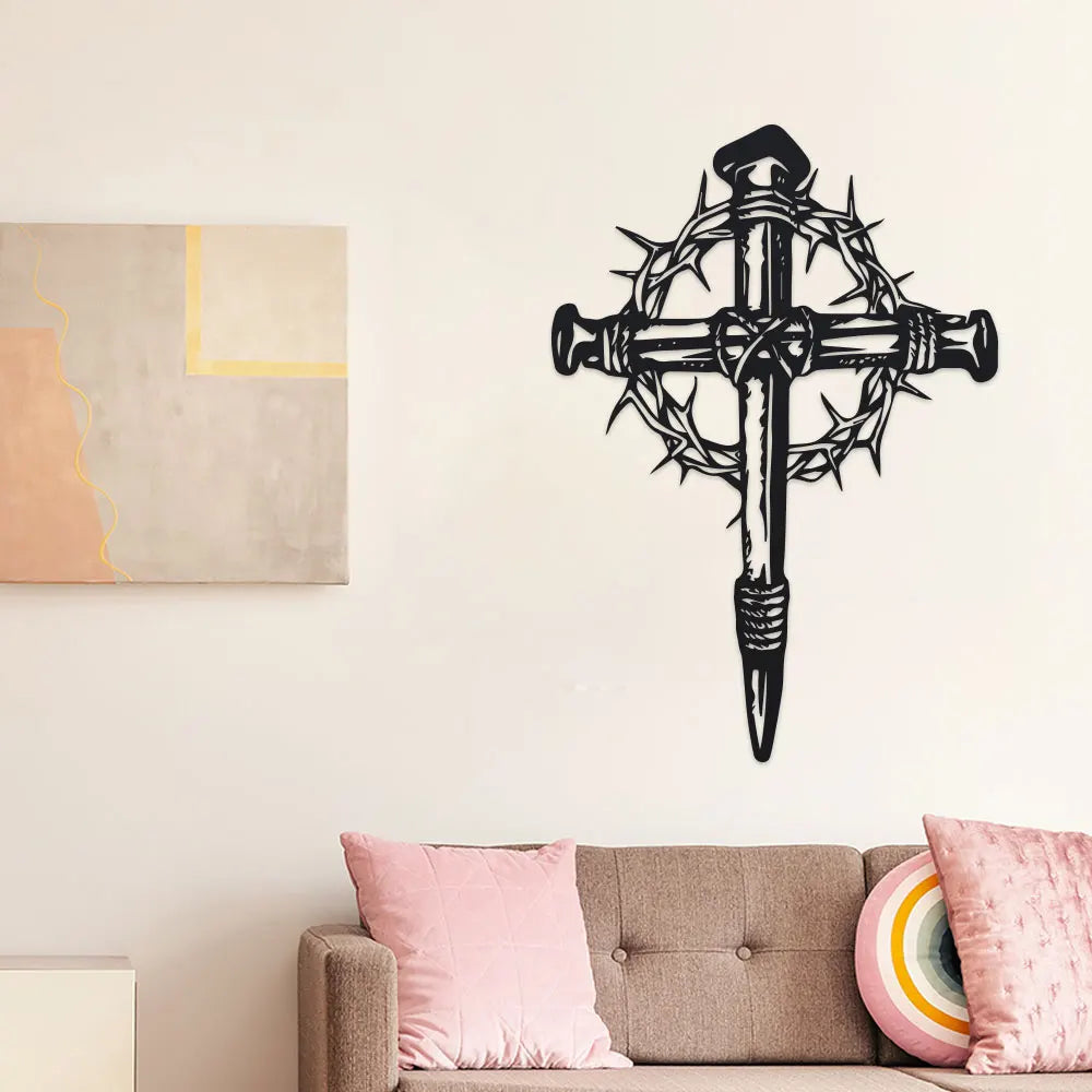 Black metal cross wall art with thorn details mounted on a white wall.