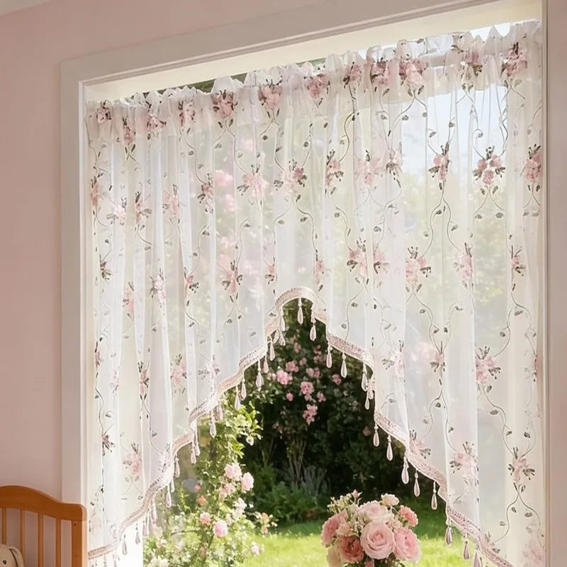 Elegante Dreiecks-Spitze-Vorhang mit rosa Blumenstickerei und durchscheinendem Stoff in einem Fensterrahmen.