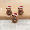 A set of festive Christmas resin decor featuring two small brown teddy bears with red hats and green plaid scarves.