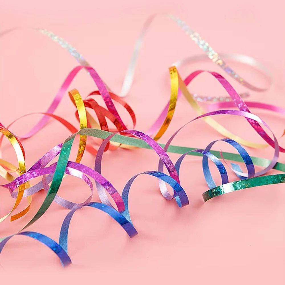 Colorful glitter curling ribbon rolls in various shades of pink, yellow, green, and blue scattered on a light background.