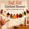 A felt garland banner featuring autumn harvest decorations including pumpkins, acorns, and maple leaves displayed on a wall.