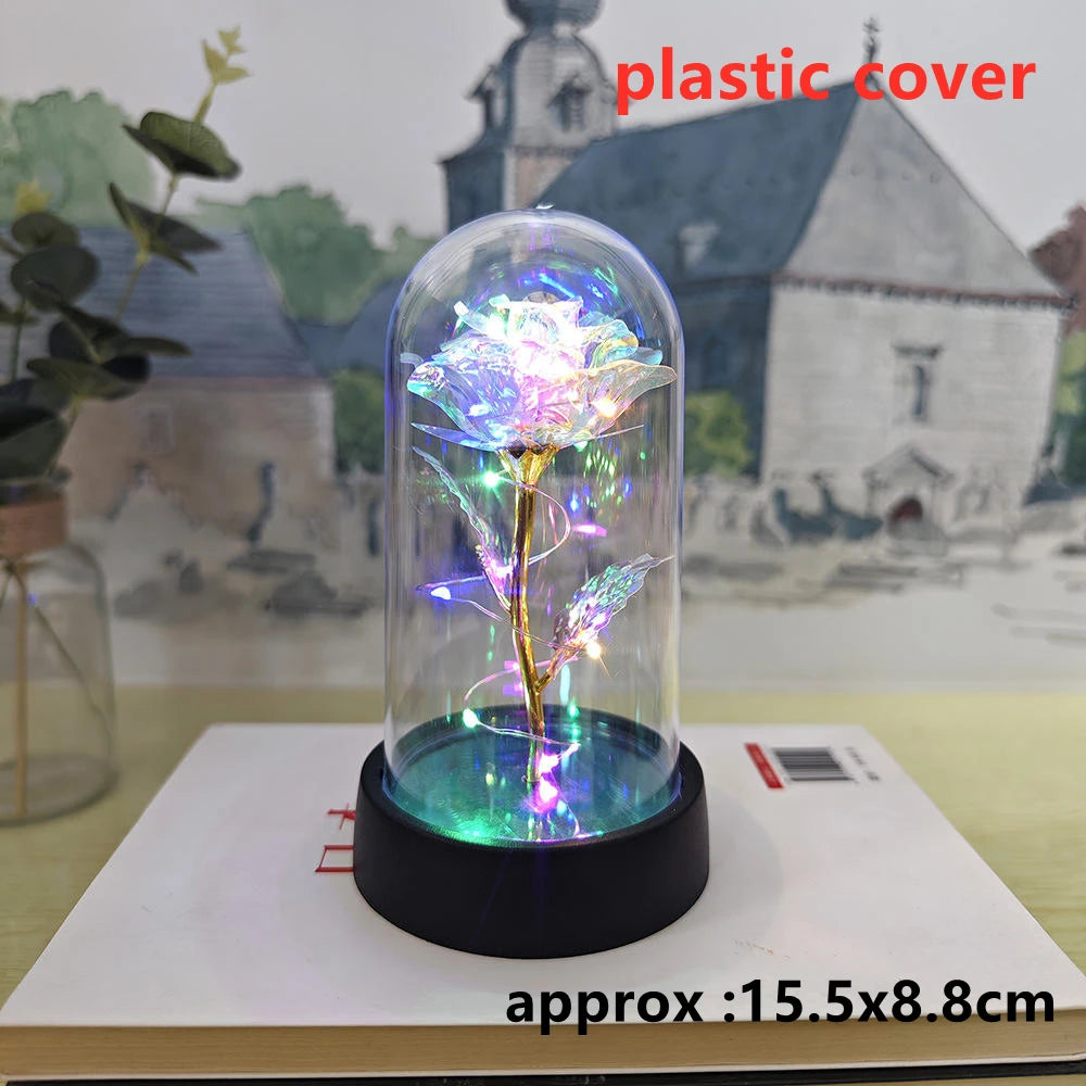 An LED galaxy rose artificial flower displayed inside a glass dome on a black base.