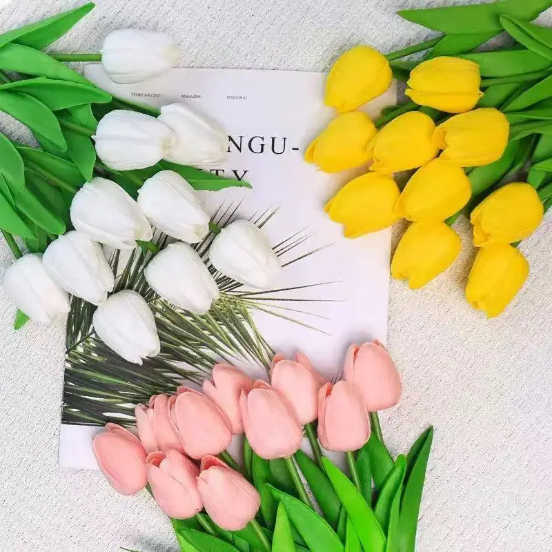 A bouquet of realistic artificial yellow tulips and pink tulips arranged on a white background with green leaves.