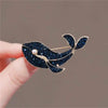 A dark blue vintage marine life brooch pin featuring a whale design and a pearl detail.