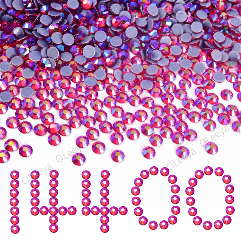 A pile of mixed size crystal and glass rhinestones in shades of pink, purple, and red.