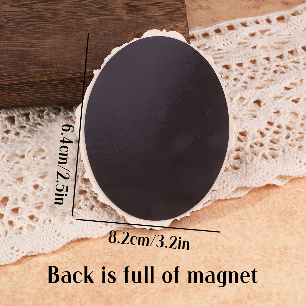A black oval fridge magnet with a white decorative edge is shown resting on a beige surface.