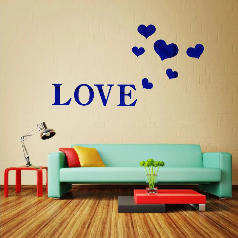 A wall decorated with blue heart stickers spelling the word LOVE above a teal sofa and a red coffee table.