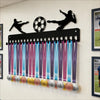 A black metal medal display rack with 20 hooks for wall mounting, featuring soccer player silhouettes above.