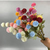 Un ramo de flores artificiales de crisantemo y diente de león en tonos rosa, púrpura, amarillo y azul.