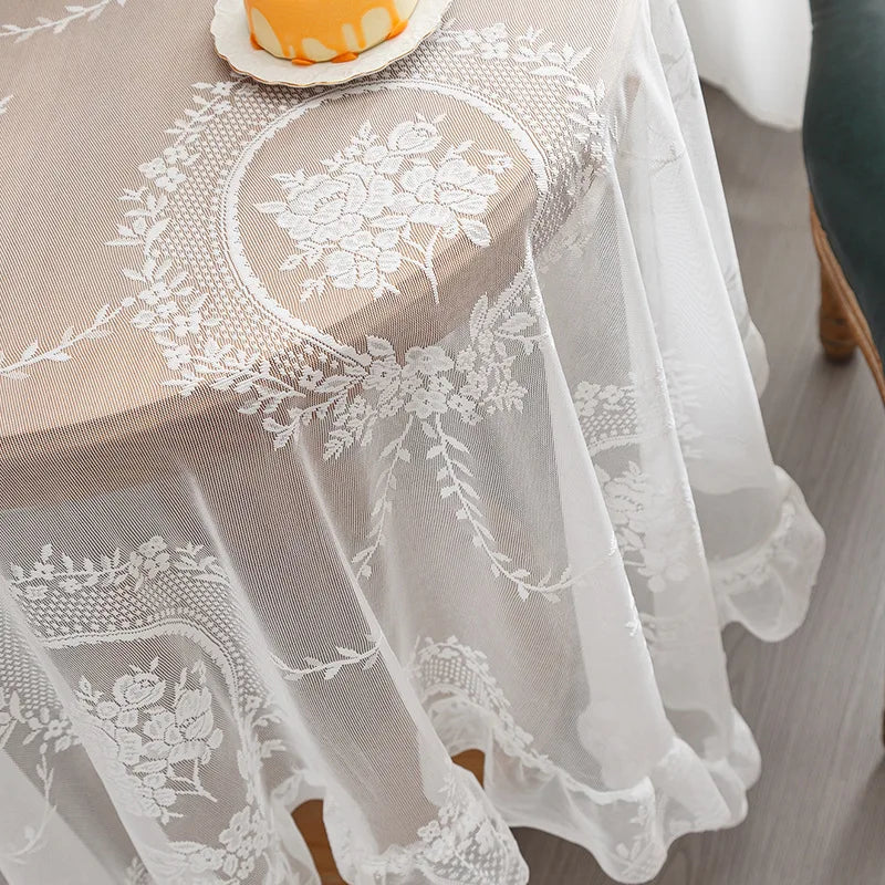 Elegant white floral lace tablecloth covering a round table with a cake.