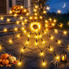 A glowing orange Halloween spider web made of LED string lights on a stone path with pumpkins and a spider.