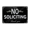A black metal wall sign with white text that reads NO SOLICITING Thank you