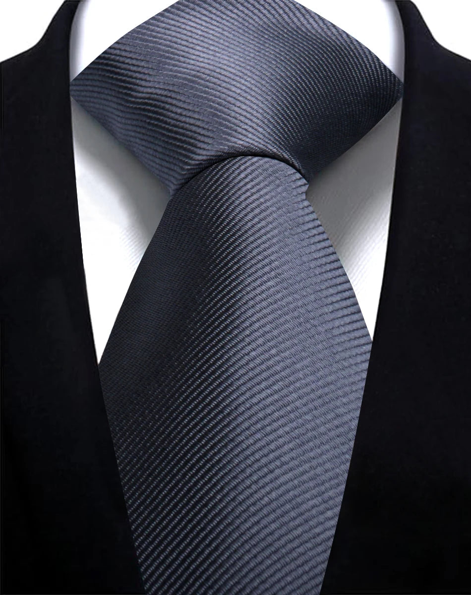 A close-up shot of a dark gray silk necktie tied in a knot against a black suit jacket.