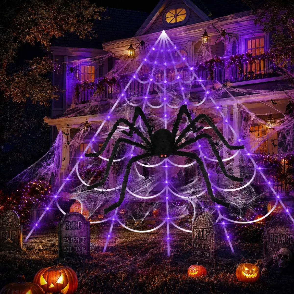A large purple spider web illuminated by lights in front of a house with Halloween decorations.