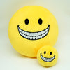 A yellow plush doll shaped like a smiling face with a wide, toothy grin.