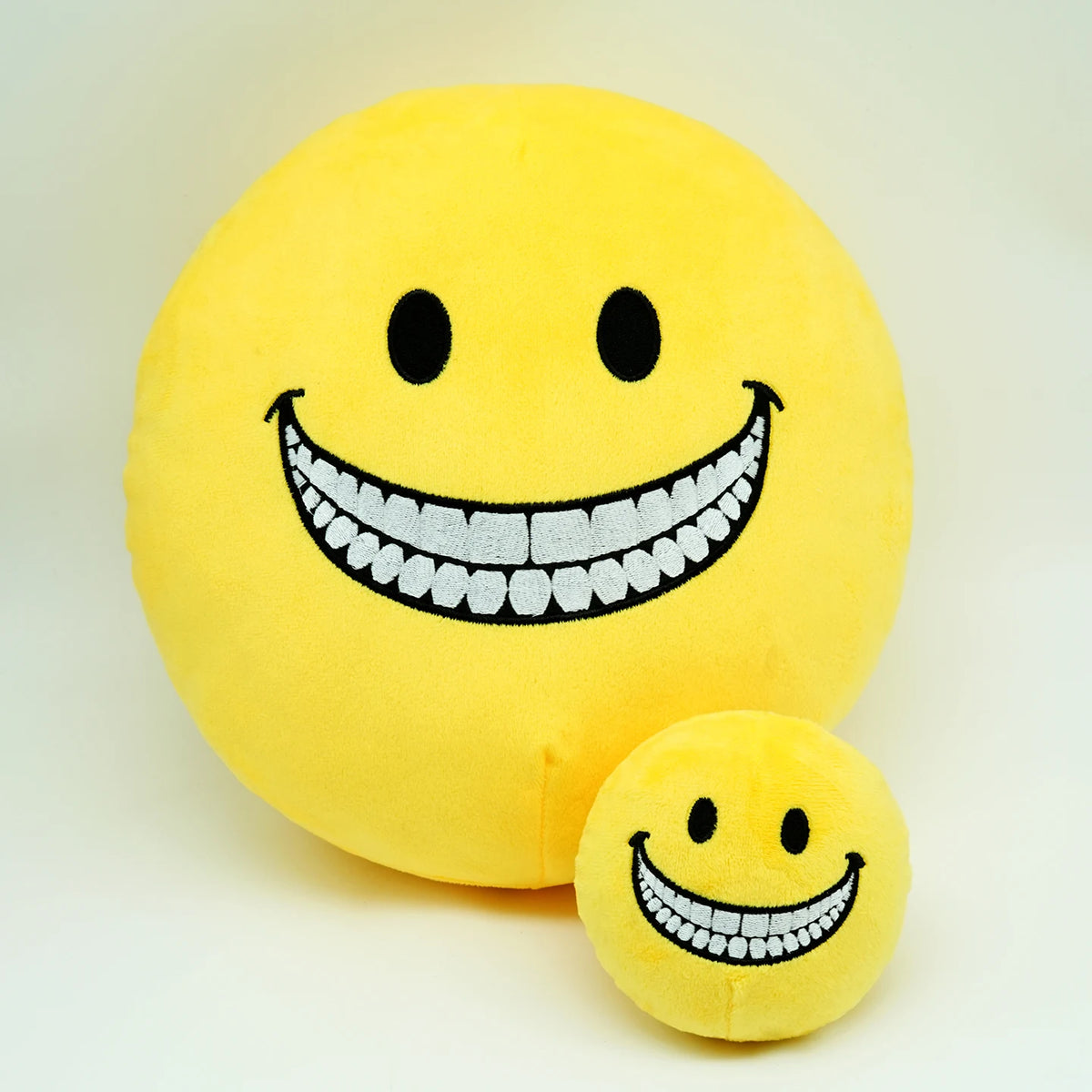 A yellow plush doll shaped like a smiling face with a wide, toothy grin.