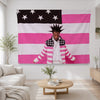 A person wearing a striped jacket stands in front of a large American flag banner featuring pink and white stripes and stars.
