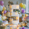A white LED marquee number frame shaped like the number 5 is displayed on a table surrounded by balloons and candles.