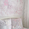 A white wall tapestry featuring a sweet dream theme with pink and white cartoon characters and flowers above a bed.