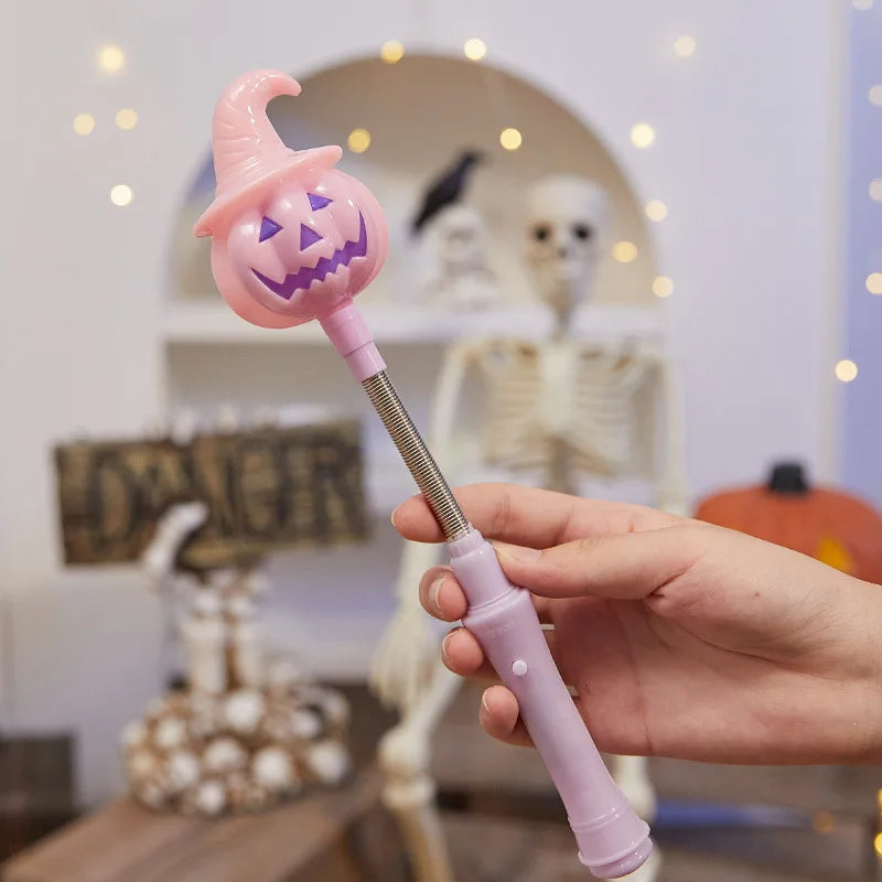 Une main tient un bâton lumineux rose en forme de citrouille pour décoration d'Halloween.